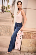 Load image into Gallery viewer, Woman wearing a sequin cami and blue jeans carrying a light pink jacket standing against a wall in an outdoor setting.
