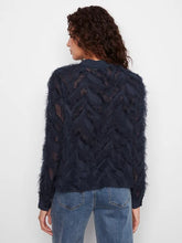 Load image into Gallery viewer, A woman modeling the back of a navy fringe blouse and blue jeans against a white wall.
