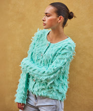 Load image into Gallery viewer, Woman wearing a fringed mint green cardigan and jeans against a beige background.
