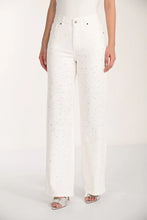 Load image into Gallery viewer, Model wearing a white top, sparkly off -white jeans and silver sandals against a white background.
