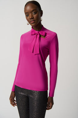 The Joseph Ribkoff long sleeve top features a slim silhouette, bow detail at the neckline, and an ultra-soft, stretchy fabric, allowing you to flaunt a feminine appearance. Ideal for wearing alone or for blending with a blazer, its design ensures a comfortable fit while elevating your look.  Color- Opulence Fuchsia. Bow design detail at the neck. Keyhole neckline. Fabric -96% Polyester, 4% Spandex.