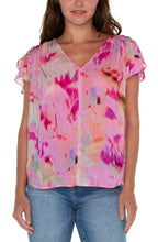 Load image into Gallery viewer, This woven tee is the perfect blouse to take you from season to season. Featuring a shirred back, v-neckline, and flirty petal sleeves, this top is a standout in vibrant colors.! Drawstring details at the shoulders create a fun and modern look. 
