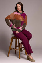 Load image into Gallery viewer, Woman sitting on a stool wearing a colorful abstract print sweater, purple pants and olive suede heel shoes against a plain background.
