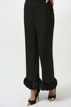 Load image into Gallery viewer, Model wearing black pleated pants with circle appliques at the hems against a white background.
