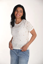 Load image into Gallery viewer, Woman wearing a short sleeve off-white open knit top with gold jewels and blue jeans on a white background.
