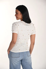 Load image into Gallery viewer, Woman wearing a short sleeve off-white open knit top with gold jewels and blue jeans on a white background.
