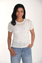 Load image into Gallery viewer, Woman wearing a short sleeve off-white open knit top with gold jewels and blue jeans on a white background.
