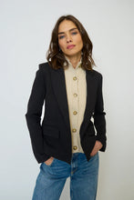 Load image into Gallery viewer, Woman wearing a black blazer and beige dickey and blue jeans against a white background.
