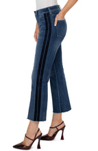Load image into Gallery viewer, Our Hannah Crop Flare combines vintage inspiration with contemporary detailing, boasting a velvet trim for a modernized look. The cut hem of the medium washed denim elongates the silhouette while elevating the style. Make a statement and match it with the coordinating Denim Jacket for a complete ensemble.  Color- Gilmore; dark blue with fading. 27” Inseam. Mid-rise. Velvet trim down the leg. Set-in waistband with belt loops. 5-Pocket styling details. Zip-fly and single logo button closure.
