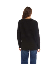 Load image into Gallery viewer, Woman wearing a black sweater and blue jeans against a white background.
