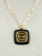 Load image into Gallery viewer, The recognizable gold and black Chanel emblem speaks to the timeless elegance and luxury of this iconic design. This unique Ina Iconic Black and Gold Vintage Coco Chanel Button Necklace is a remarkable addition to any ensemble, featuring a rare design and rich historical value. Experience a unique and eye-catching look with this one-of-a-kind button necklace.
