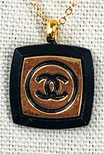 Load image into Gallery viewer, The recognizable gold and black Chanel emblem speaks to the timeless elegance and luxury of this iconic design. This unique Ina Iconic Black and Gold Vintage Coco Chanel Button Necklace is a remarkable addition to any ensemble, featuring a rare design and rich historical value. Experience a unique and eye-catching look with this one-of-a-kind button necklace.
