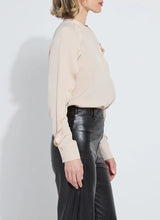 Load image into Gallery viewer, Model wearing a rose petal colored blouse with ruffle detailing and black pants against a white background.
