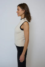 Load image into Gallery viewer, Woman wearing an ivory sleeveless top with black trim and black pants against a light gray background.
