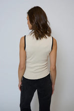 Load image into Gallery viewer, Woman wearing an ivory sleeveless top with black trim and black pants against a light gray background.
