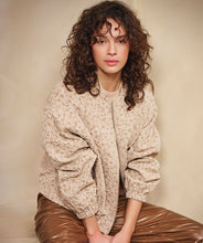 Load image into Gallery viewer, Woman wearing a beige quilted jacket and brown pants against a beige background.

