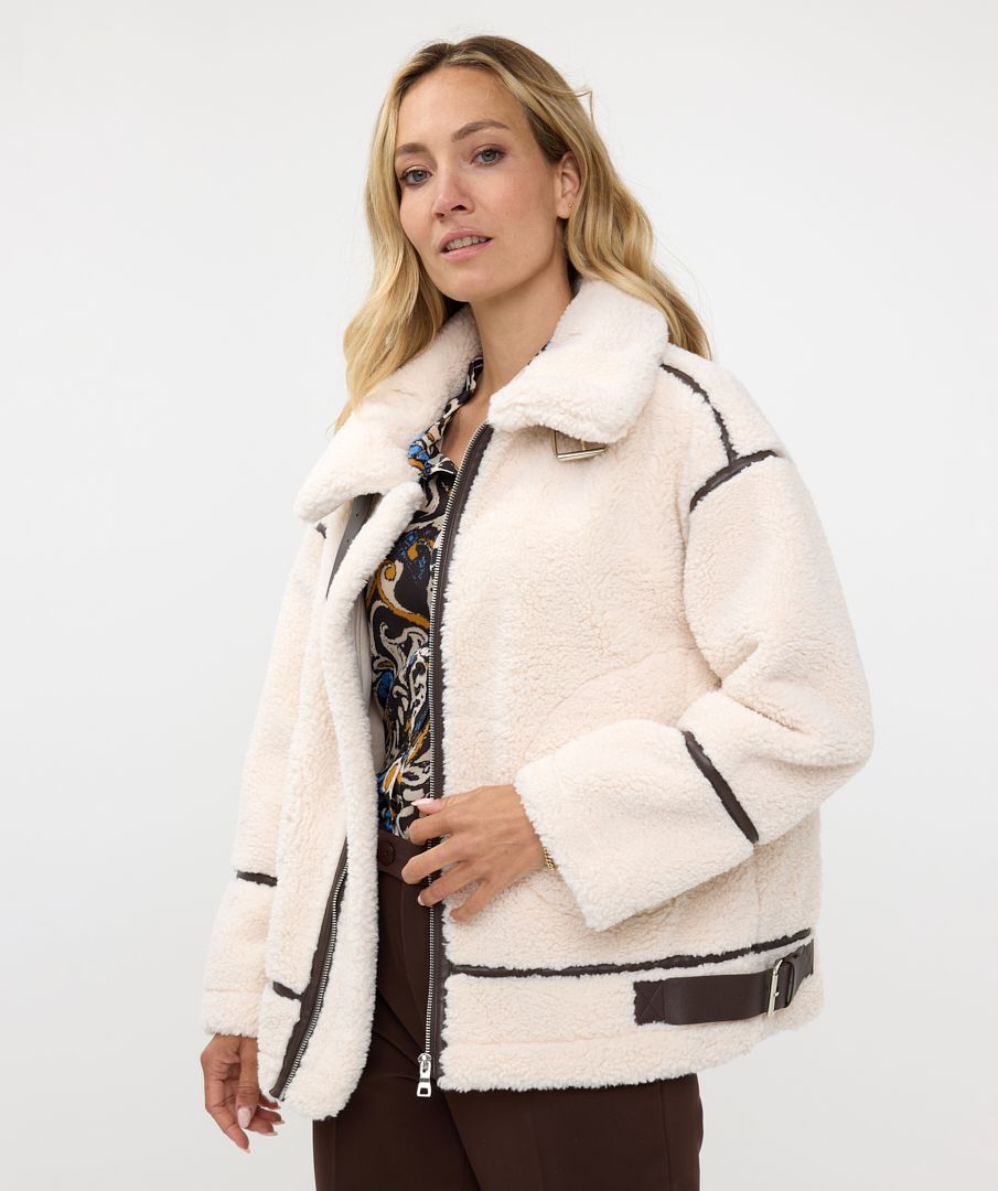 The luxurious Faux Fur Aviator Jacket in creamy ivory is a fashion statement. It boasts a plush faux fur exterior, complemented by dark brown leather accents and an elegant buckle detail for extra style. The inside is made of velvety suede that adds extra warmth. Designed with long sleeves and a zip-up closure, it's not only chic but also practical, ensuring warmth and fashion throughout the cooler seasons.