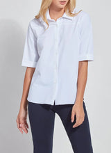 Load image into Gallery viewer, A woman wearing a white short-sleeve button-up shirt with rolled cuffs and dark navy pants, photographed against a light gray studio background.

