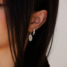 Load image into Gallery viewer, Close-up of a model's ear with two earrings including a pearl and crystal baguette drop earring against a neutral background.
