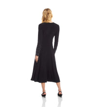 Load image into Gallery viewer, Woman in a long black dress with crystal embellishments on the sleeves and black heels against a white background.
