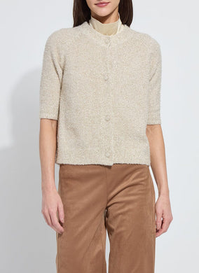 Model wearing a feather yarn, gold lurex knitted cardigan and brown pants against a white background.