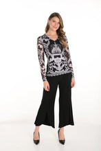 Load image into Gallery viewer, Woman wearing a black and white patterned top with black pants against a white background.
