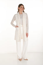 Load image into Gallery viewer, Woman wearing a long sparkle vest over a white sparkle top, white pants and beige sandals against a white background.
