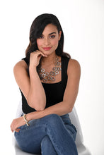 Load image into Gallery viewer, Woman wearing a black camisole tank, large silver necklace and blue jeans sitting on a chair against a white background.
