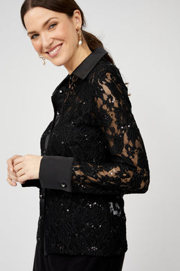 Woman wearing a black lace top with sequins against a white background.