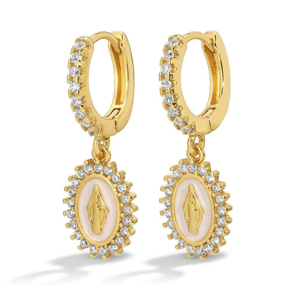 Gold huggie earrings with central white oval design and a Virgin Mary icon surrounded by small crystals against a white background.