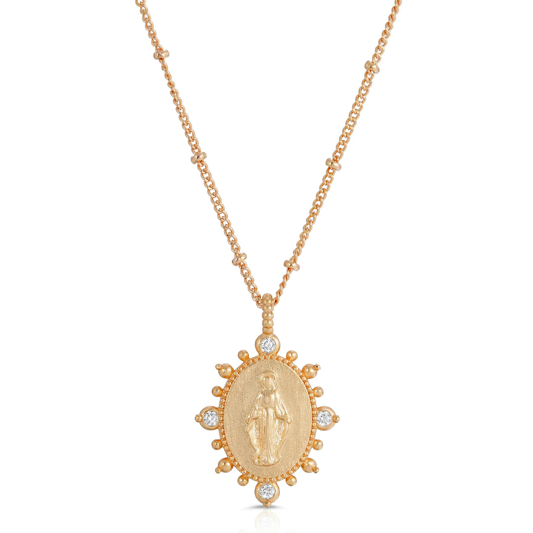 Deepen the faith with the Lady Lourdes Pendant Necklace. Features a golden metallic pendant, highlighting a portrait of the Virgin Mary surrounded by ornamental CZ accents and embellished spike details.   Color- Gold and clear. Cubic zirconia. 14K Yellow gold plating over brass. 14