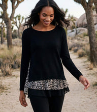 Load image into Gallery viewer, A woman walking outdoors in a desert setting wearing a black long-sleeve top with a leopard-print ruffle hem, paired with black leggings.
