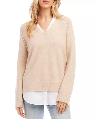 Woman wearing a layered beige sweater and blue jeans against a white background.