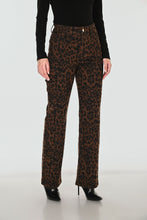 Load image into Gallery viewer, A model wearing high-waisted brown and black leopard-print pants, styled with a black long-sleeve top and black pointed-toe heels, photographed against a light gray studio background.

