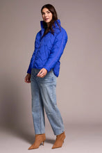 Load image into Gallery viewer, Woman wearing a blue puffer jacket, blue jeans and tan suede boots against a neutral background.
