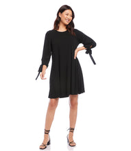 Load image into Gallery viewer, Karen Kane&#39;s Lily Swing Dress is a soft jersey-knit fabric and loose-fitting swing silhouette make it versatile enough for work hours and evening dinner. The bows placed on the sleeves adds extra interest while the side pockets offer functionality. Color- Black. 3/4 Sleeve with ties Center back invisible zipper. Side pockets. Swing dress design. Fabric -68% Acetate. 27% Polyester. 5% Spandex. Care- Dry clean.
