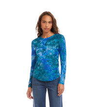 Load image into Gallery viewer, Woman wearing a bright blue tie dye patterned long-sleeve top and jeans against a white background.
