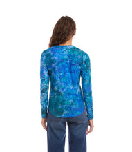 Load image into Gallery viewer, Woman wearing a bright blue tie dye patterned long-sleeve top and jeans against a white background.
