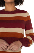 Load image into Gallery viewer, Model wearing burgundy multicolor striped crewneck sweater and blue jeans against a white background.
