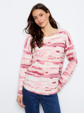 Load image into Gallery viewer, A woman wearing a long-sleeve knit sweater with a pink and white pattern, paired with blue jeans, against a plain white studio background.
