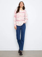 Load image into Gallery viewer, A woman stands against a white wall wearing a pink and white sweater, blue jeans, and dark brown loafers.
