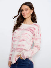 Load image into Gallery viewer, A woman wearing a long-sleeve knit sweater with a pink and white pattern, paired with blue jeans, against a plain white studio background.
