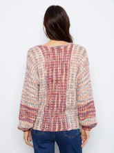 Load image into Gallery viewer, A woman viewed from the back wearing a textured, multicolor knit sweater with vertical stripes in pink, red, beige, and blue, paired with blue jeans against a plain white background.
