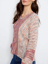 Load image into Gallery viewer, A woman wearing a long-sleeve knit sweater with a multicolor pattern paired with blue jeans against a plain white background.

