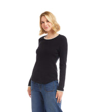 Load image into Gallery viewer, Woman wearing a black long-sleeve top with white trim and blue jeans against a white background.
