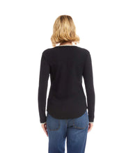 Load image into Gallery viewer, Woman wearing a black long-sleeve top with white trim and blue jeans against a white background.

