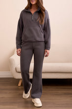 Load image into Gallery viewer, Woman wearing a gray casual zip up top, matching gray jogger and sneakers standing in a room with a beige couch.
