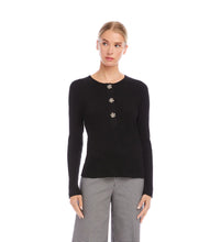 Load image into Gallery viewer, Woman wearing a black long sleeve top with decorative buttons and plaid black and white pants on a white background.
