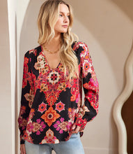 Load image into Gallery viewer, Woman wearing a colorful print blouse, gold necklace and blue jeans against a neutral background.
