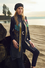 Load image into Gallery viewer, Woman in a long vest with a unique design standing on a beach.
